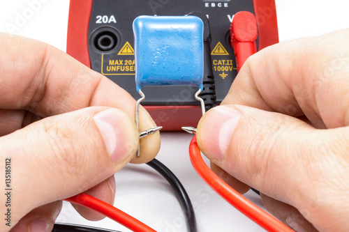Testing capacitor with multimeter on a white background