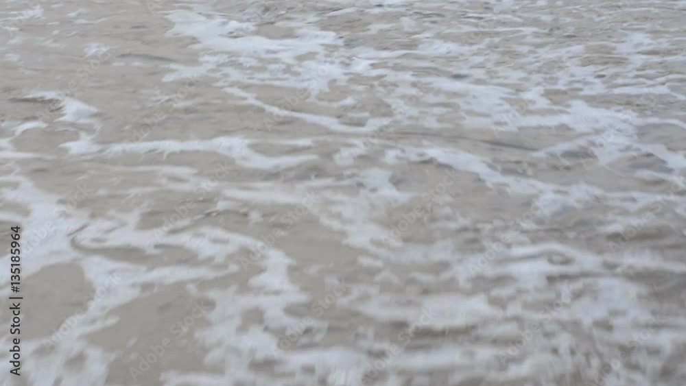 Soft, gentle ocean surf rolls over a sandy shoreline, creating a peaceful scene.. Soft, gentle ocean surf rolls over a sandy shoreline, creating a peaceful scene..