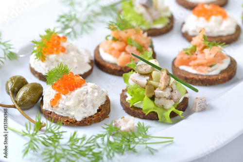 Leckeres Fisch-Fingerfood mit Lachstatar, Matjestatar und Forellencreme mit Kaviar - Finger food with salmon tartar, trout mousse with caviar and herring salad on pumpernickel bread 
