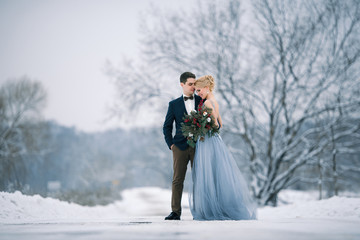 Bride and groom among snowy landscape.