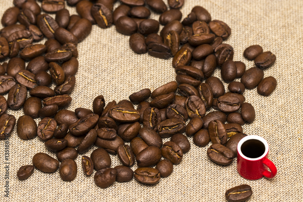 Heart of coffee beans and a Cup on burlap background Heart of coffee beans and a Cup on burlap background