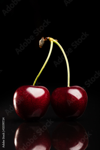 Two juicy fresh cherries on black background