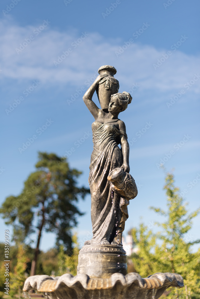 Fountain in the city park, woman with a pitcher