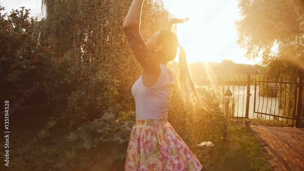 Slow motion footage of happy laughing woman enjoying summer rain at sunset