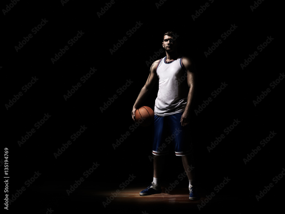 basketball player standing in durkness on parquet with ball basketball player standing in durkness on parquet with ball
