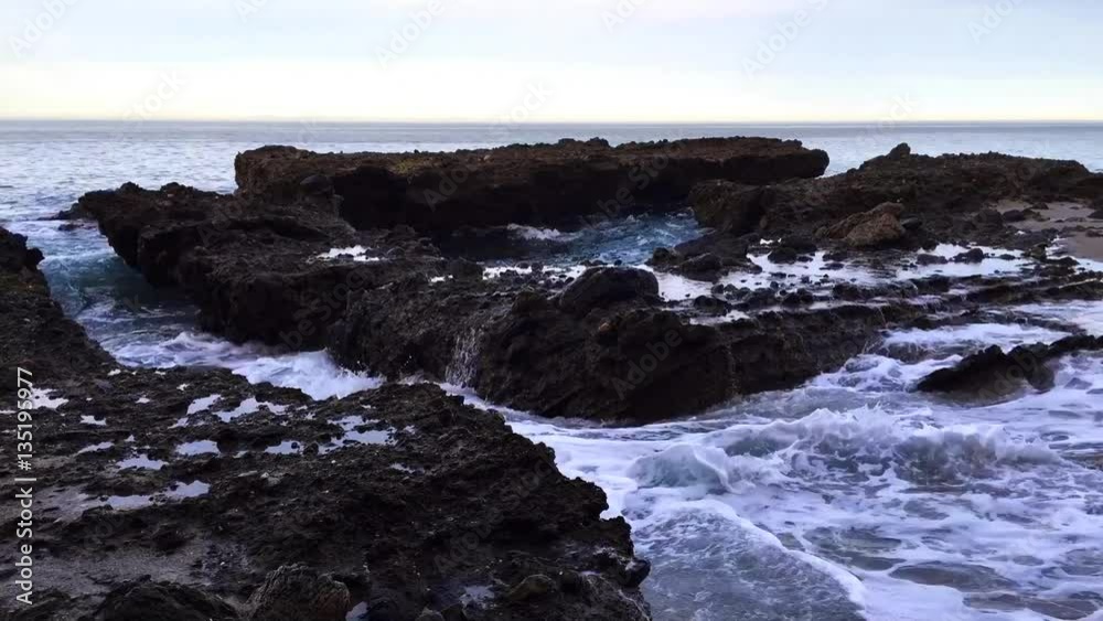 Wide view of ocean reef crevice time lapse with water powering through the canyons and pools as waves make their way to shore..