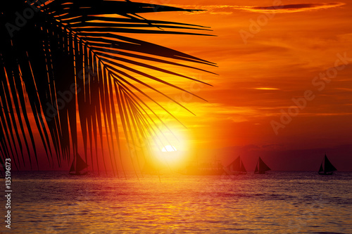 Sunset on beach with sailing boats