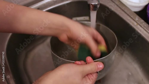 Teenager boy washing pan photo