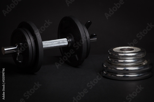 Dumbbell and barbell discs for workout on black background