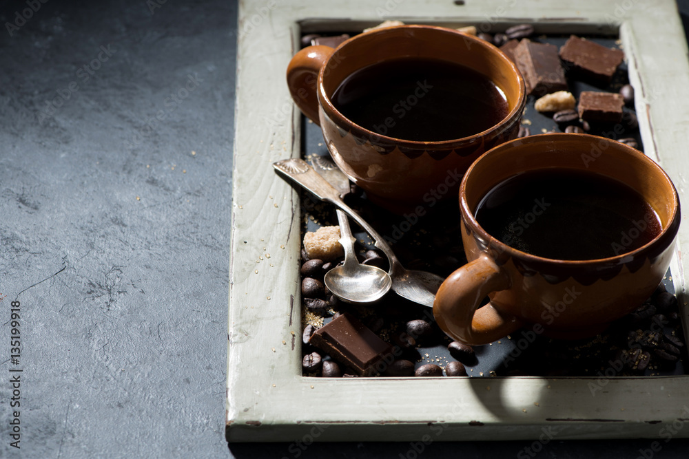 fresh black coffee in a cups and chocolate on blackboard