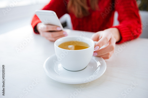 Cropped image of lady sitting in cafe holding tea.