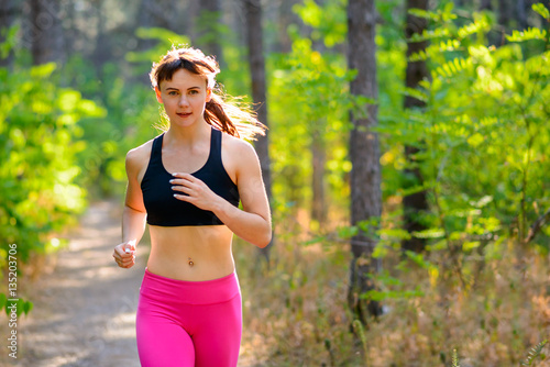 Young Woman Running on the Trail in the Beautiful Wild Forest. Active Lifestyle Concept. Space for Text.