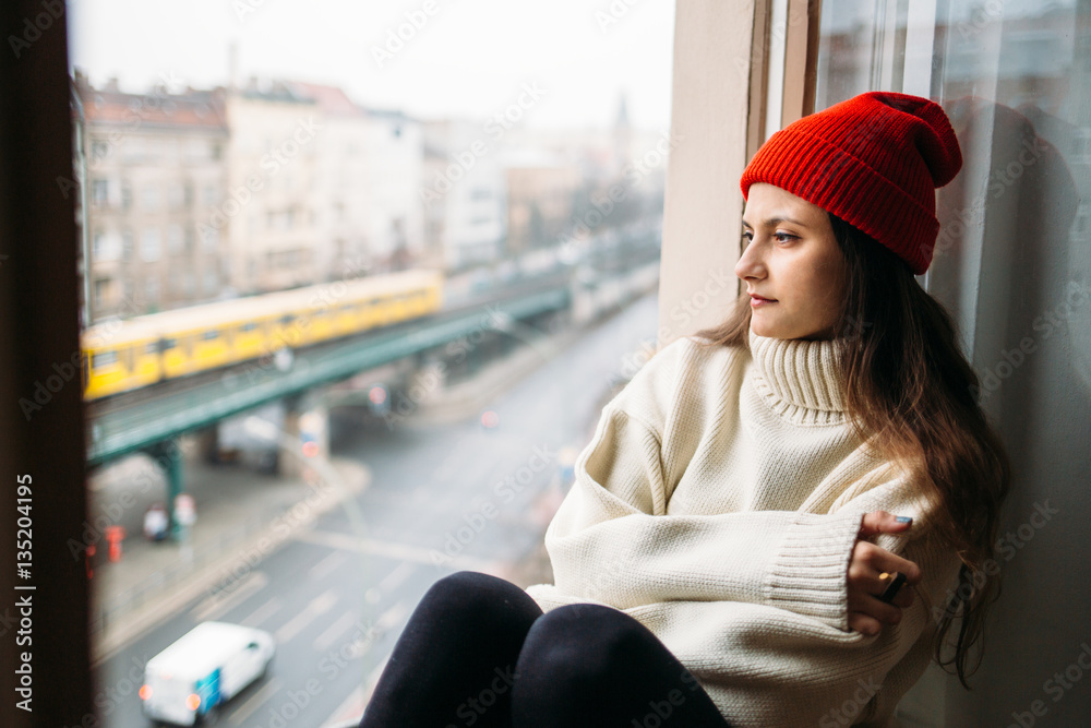 Hipster girl sitting close to window and looking Hipster girl sitting close to window and looking