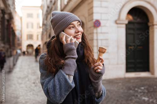 Woman with ice cream talking on mobile phone in city