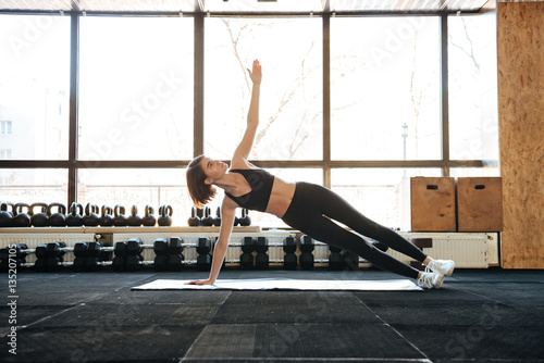 Fototapeta Naklejka Na Ścianę i Meble -  Sportswoman doing exercises on mat in gym