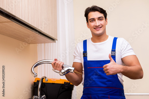 Young repairman working at the kitchen