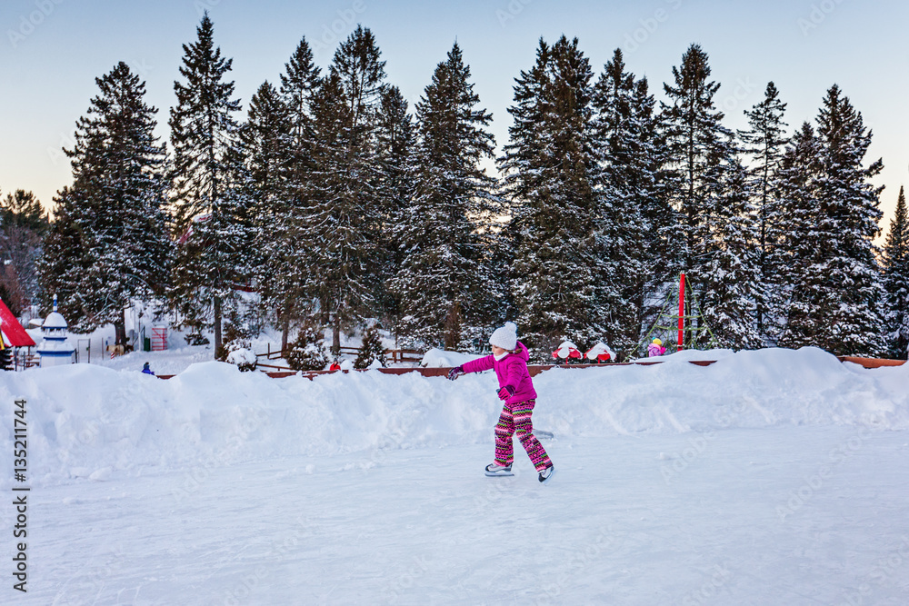 Little girl in warm clothes on an ice skating rink outdoors. Winter activity. Little girl in warm clothes on an ice skating rink outdoors. Winter activity.
