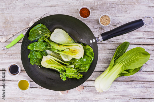 Fotografie Fried Chinese cabbage pak choi in wok on wooden background.