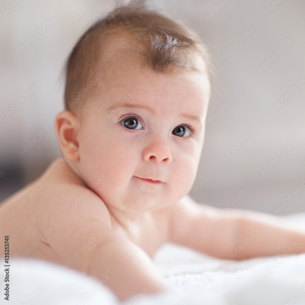 Close up portrait of cute baby. Adorable baby in white sunny bed Close up portrait of cute baby. Adorable baby in white sunny bed