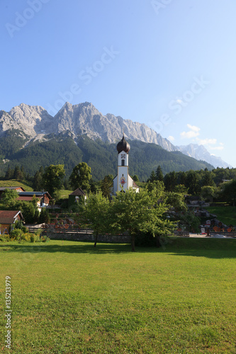 A beautiful church and cemetery in the village Grinau with Zugspitze in the background