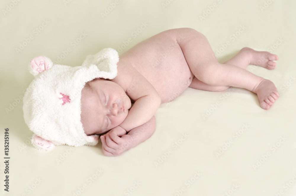 Newborn of 10 days with a bonnet sleeping in a bed. Newborn of 10 days with a bonnet sleeping in a bed.