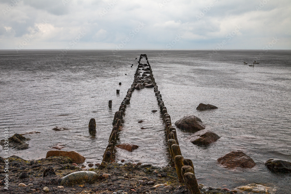 Fototapeta premium Old broken pier at stone beach of the Baltic sea