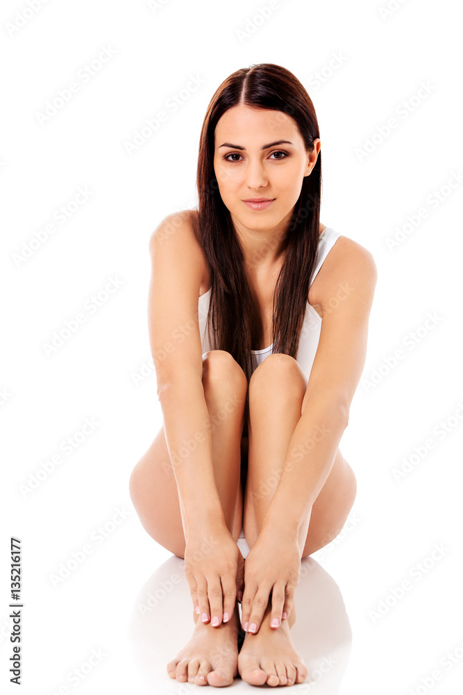 Fototapeta premium Portrait of sexy brunette in white underwear sitting on white background.