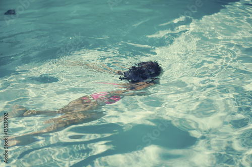 The little Italian girl under the water of pool in the summer