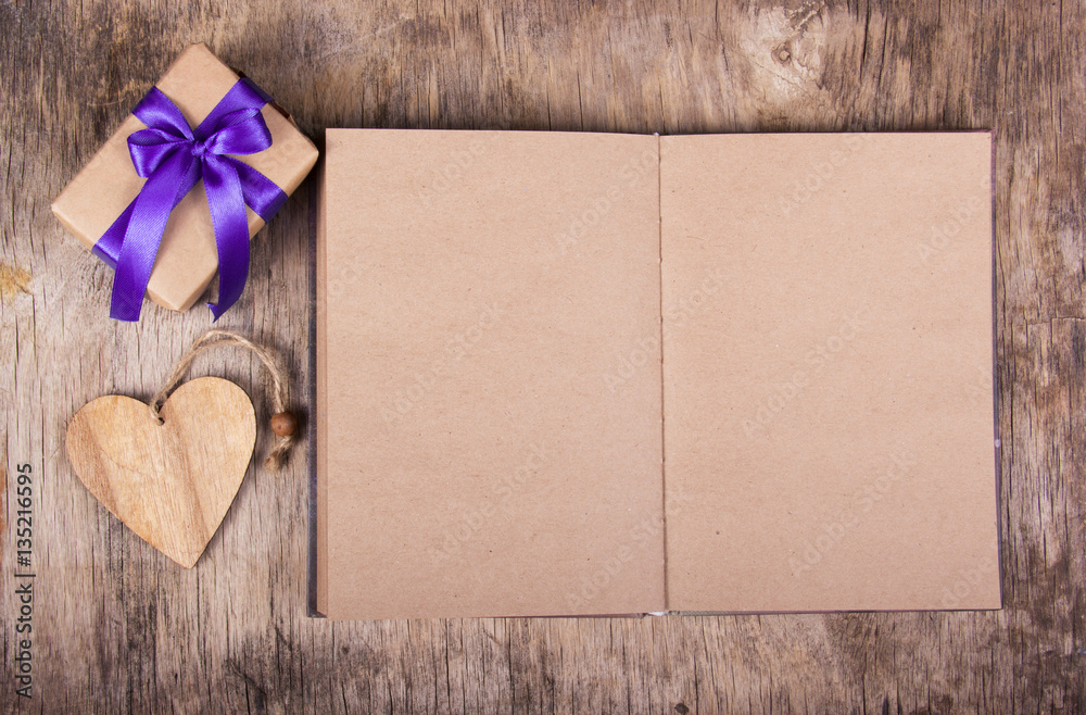 Open notebook with blank pages. Box with a gift and Valentine on the old wooden background. Valentine's day. Copy space. Open notebook with blank pages. Box with a gift and Valentine on the old wooden background. Valentine's day. Copy space.