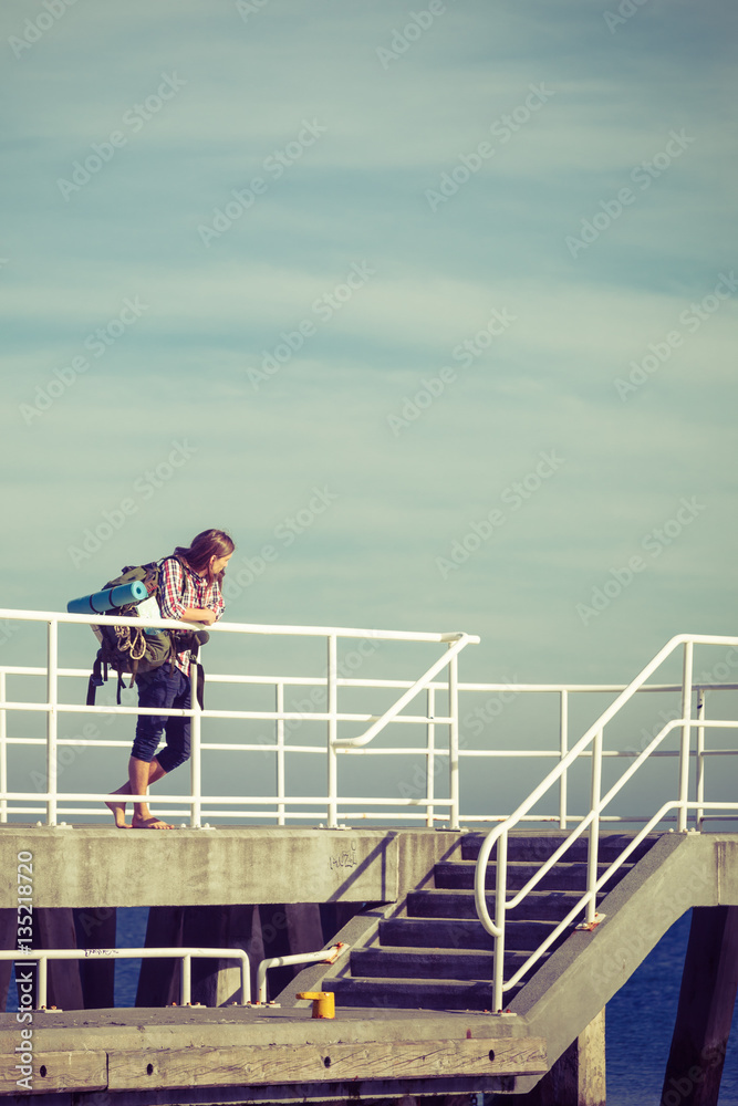 Man hiker with backpack on pier, sea landscape Man hiker with backpack on pier, sea landscape
