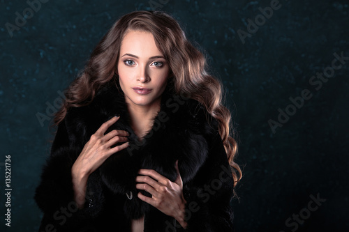 Young brunette woman with perfect natural makeup and hair style wearing furs. fashion beauty portrait 