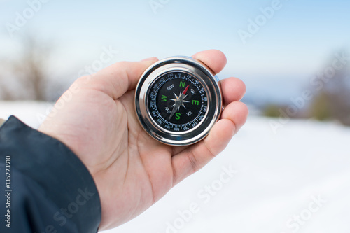 Man using a compass on snowy mountain