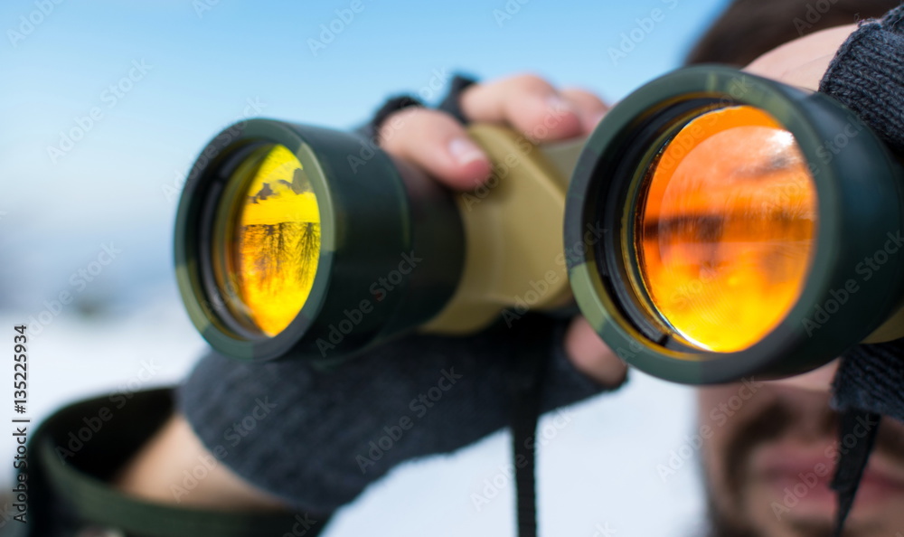 Man using binoculars outside on a winter day Man using binoculars outside on a winter day
