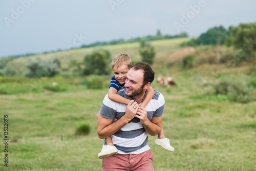 Child sitting on the shoulders of his father. Happy man with cute little baby boy