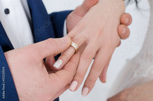 Groom is putting on a ring on bride's finger
