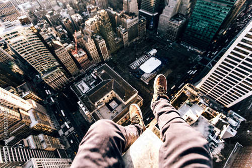 Point of view image of persons legs on top of skyscraper photo
