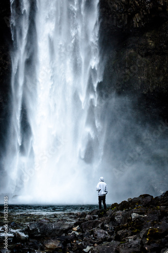 Rear view of person standing by waterfall