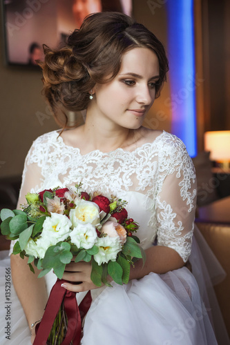 Young and beautiful bride with flower bouquet in hotel