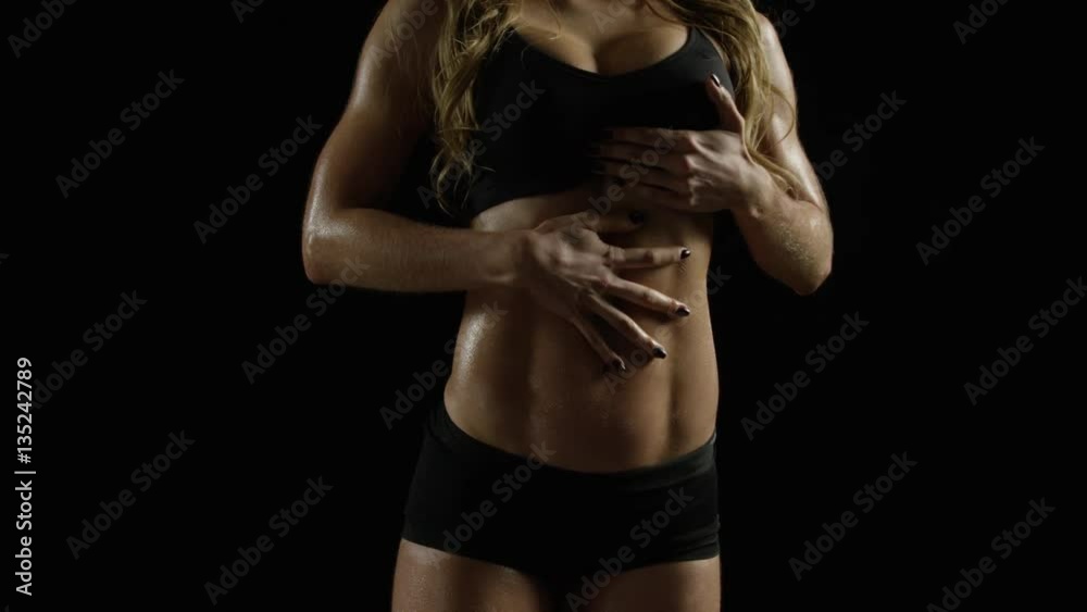 Attractive woman with toned abs rubs her belly. Dolly into CU.