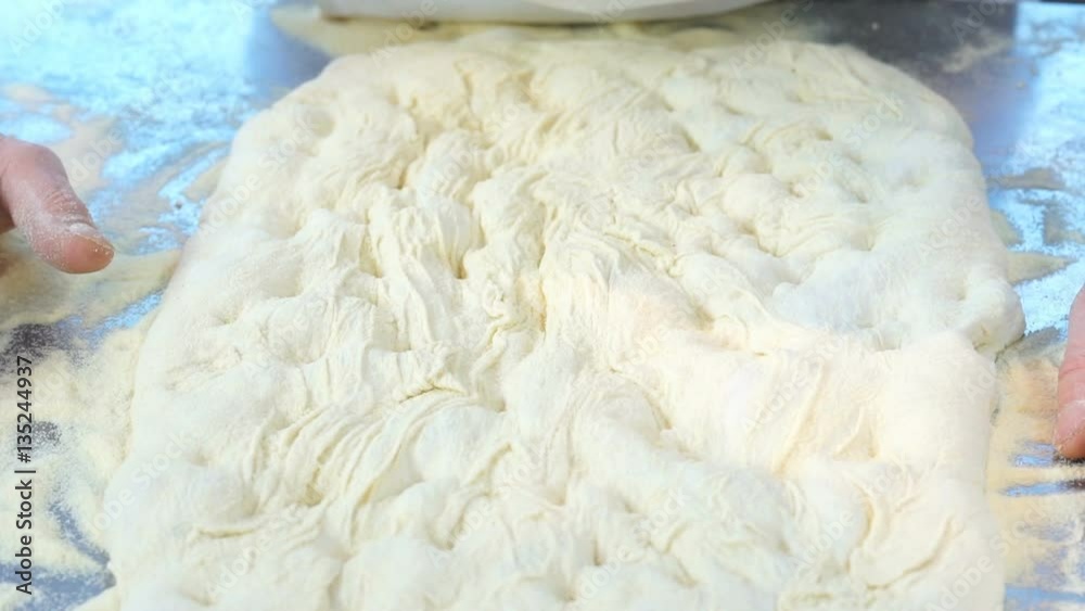 man stretches out dough focaccia on the table full of flour man stretches out dough focaccia on the table full of flour
