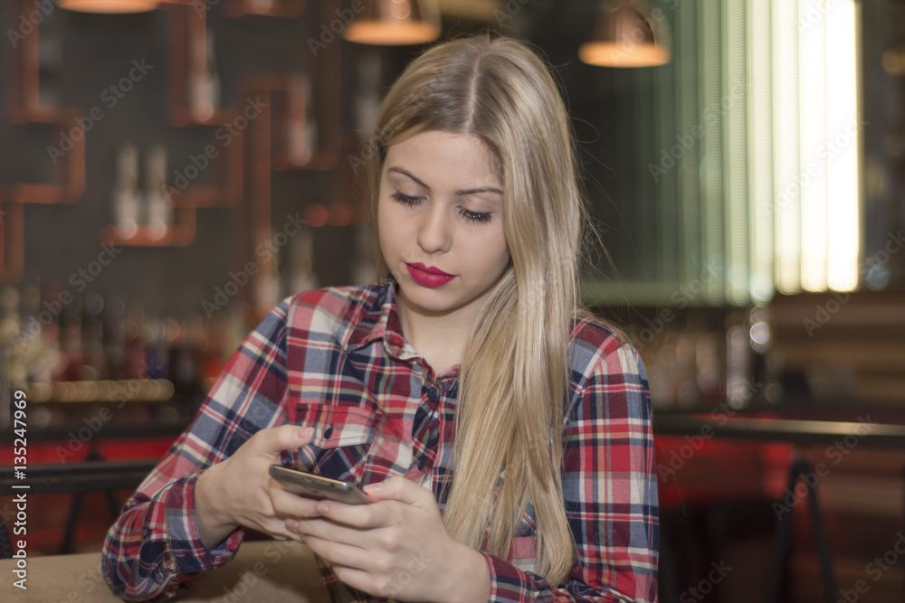  Young Woman typing write message on smart phone in a modern cafe.