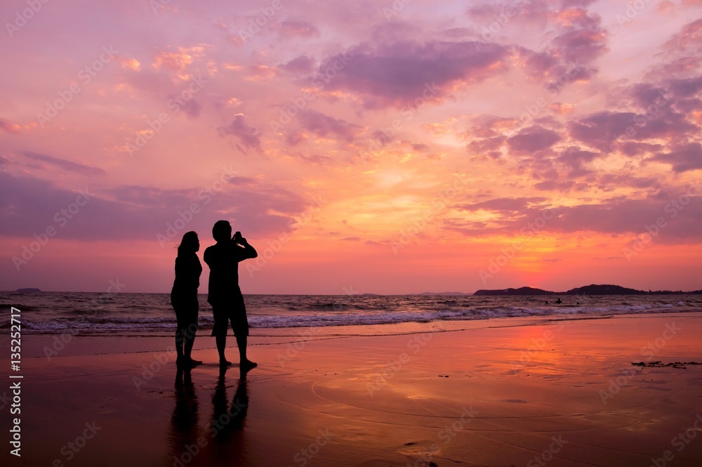 Silhouette of romantic couple standing on the beach at sunset