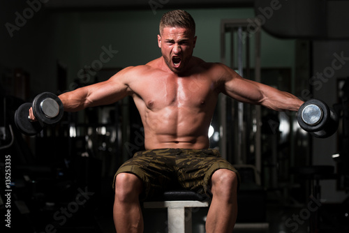 Man In The Gym Exercising Shoulder With Dumbbells