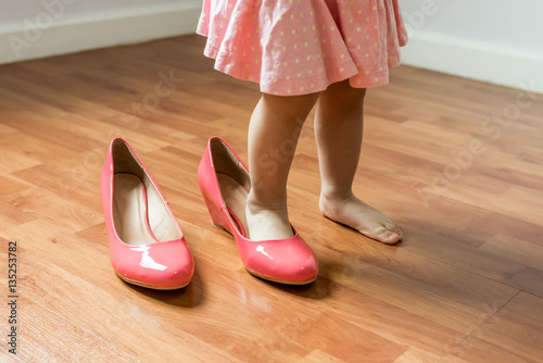 Baby girl wearing her mother's shoes