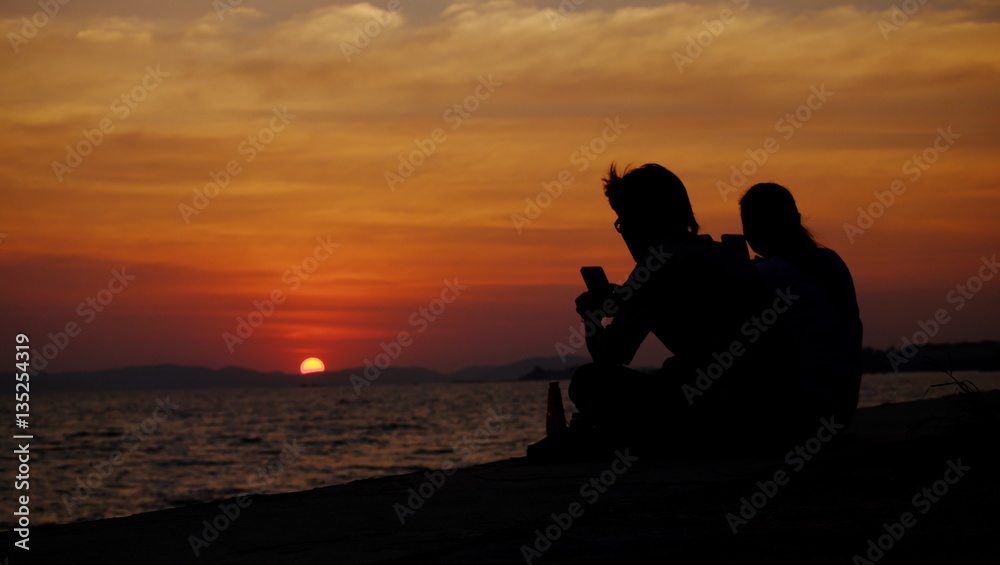Men and Women Sitting on the beach Watching the sunset. Twilight sky background