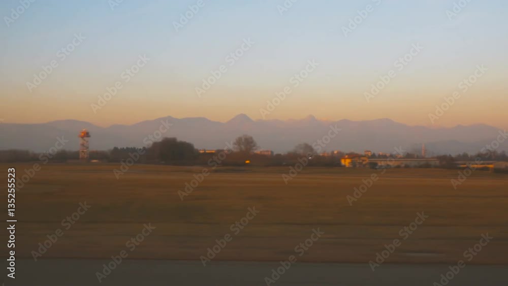 Aircraft taking off and sunset landscape (POV) from Bergamo Orio al Serio Airport near Milan in Italy Aircraft taking off and sunset landscape (POV) from Bergamo Orio al Serio Airport near Milan in Italy