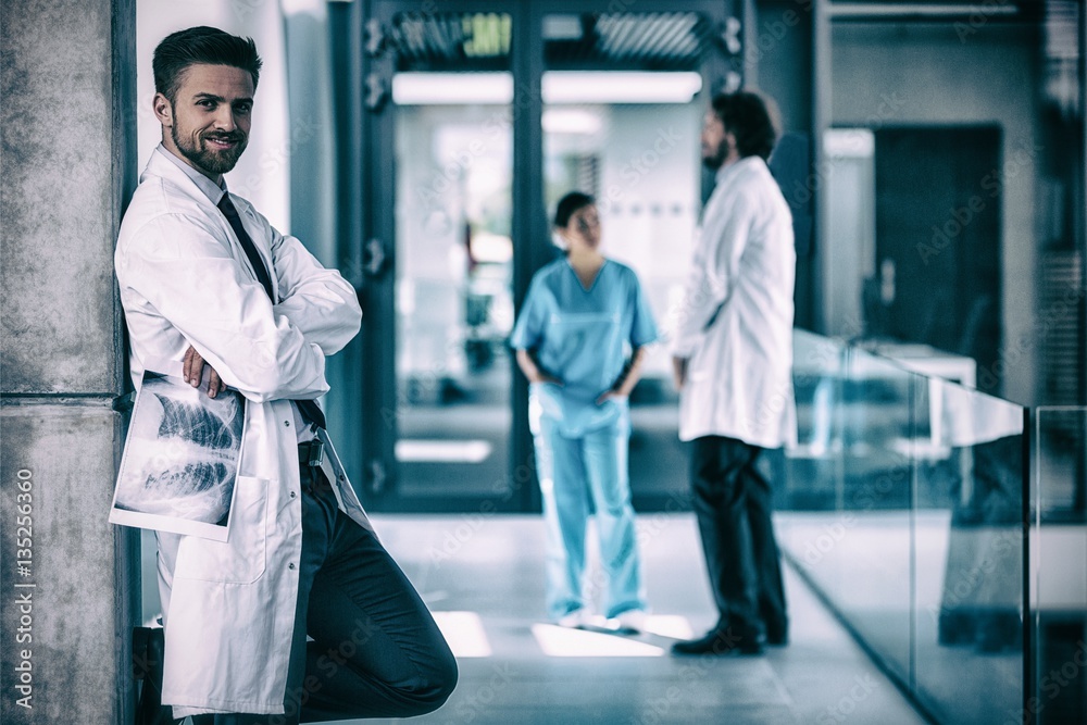 Portrait of doctor holding x-ray while standing against wall Portrait of doctor holding x-ray while standing against wall