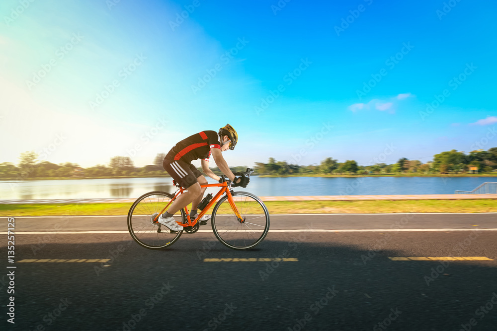 Obraz premium Man riding bicycle on the road and river side in the park.