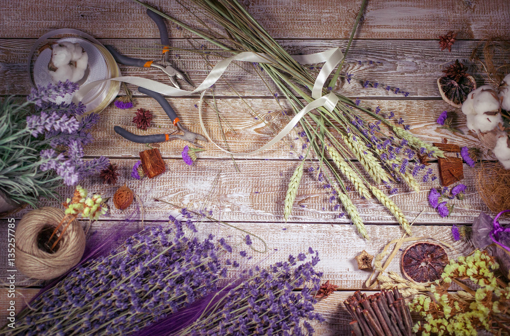 Obraz premium Florist workplace. Flowers and accessories on wooden table. Background vintage end retro toning . Top view. Flat lay composition