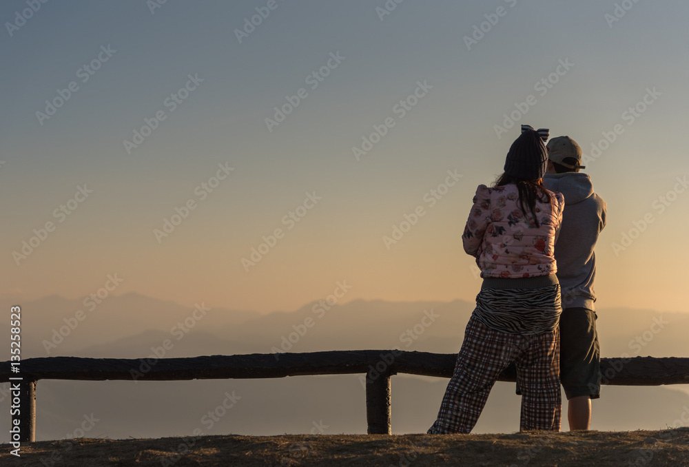 Man and Woman watching the sunrise on the mountain.